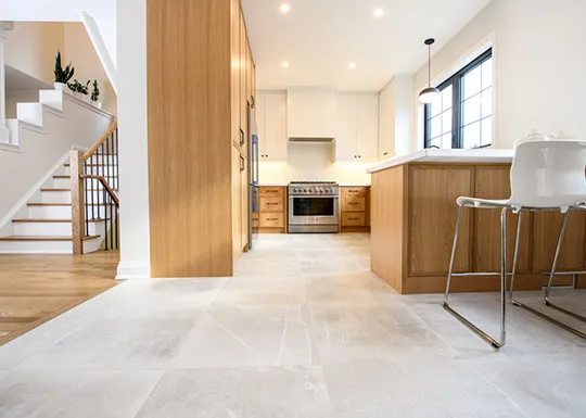 Modern kitchen with light ceramic flooring and wooden cabinetry.