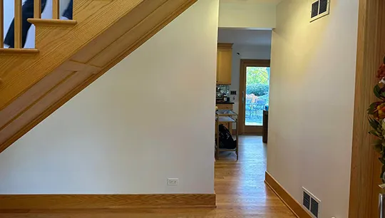 Bright hallway with clean drywall and natural light from kitchen.