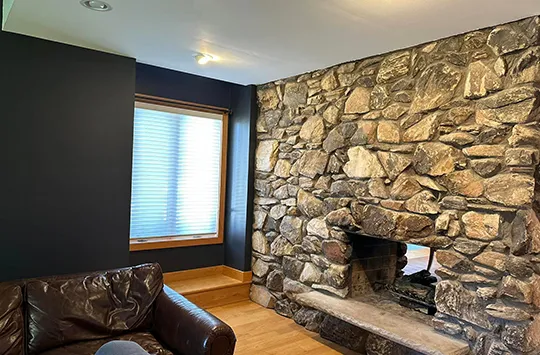 Room interior with stone fireplace, painted wall, and a sofa.