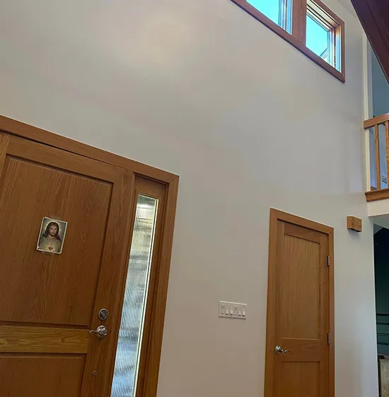 Bright entrance hall showcasing smooth custom drywall and wooden doors.