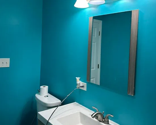 Bathroom interior with a sink, blue painted wall, and a mirror.