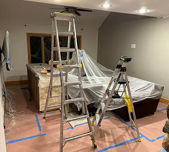 Home remodeling in progress with ladders, plastic cover, and tools.