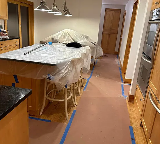 Renovated kitchen with protective coverings and painter's tape.