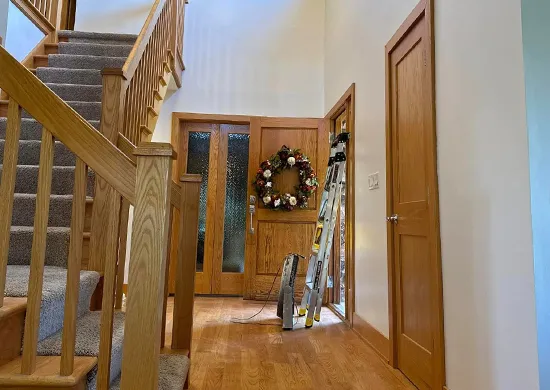 Bright hallway with wooden stairs and ladder representing home remodeling.